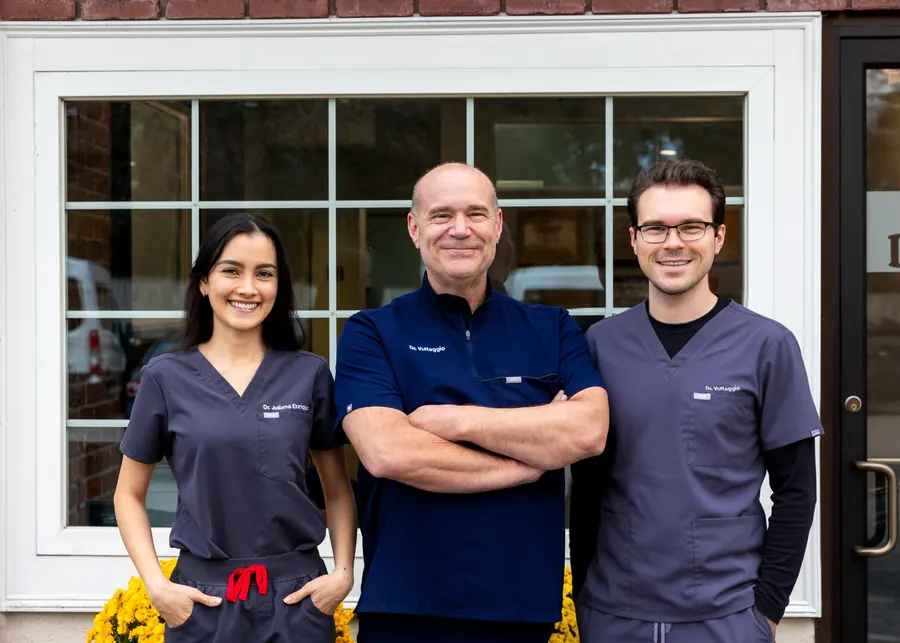 Dr. Juliana Enriquez, Dr. Stephen Vultaggio and Dr. Andrew Vultaggio smiling outside a brick building.