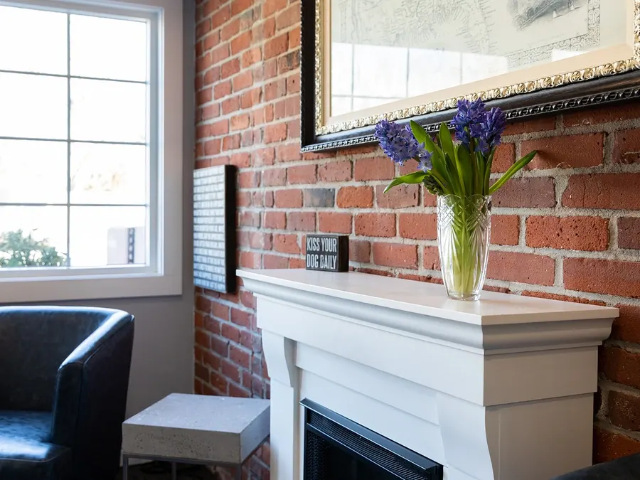 The front lobby at Vultaggio Dental: a brick wall, a fireplace and fresh flowers by the window.